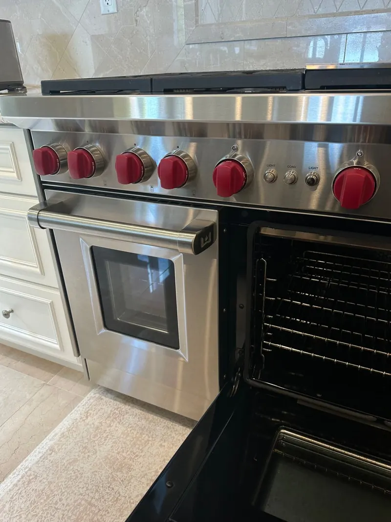 Wolf oven open for service with the red control knobs visible